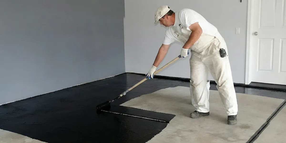 basement waterproofing professional applying waterproof coating to protect a basement floor in Madison, WI